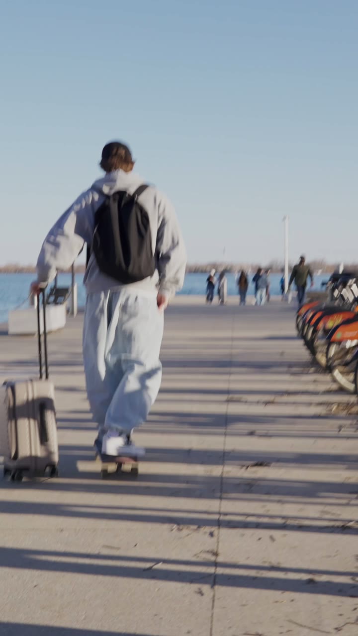 Cody French skateboarding along the waterfront with a carry-on